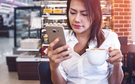 jeune femme buvant un café et utilisant une smartphone